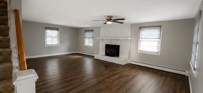 Open living room with grey walls, dark hardwood floors and a white fireplace