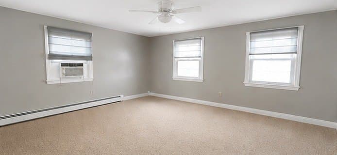 Bright empty living room painted soft grey with white baseboards