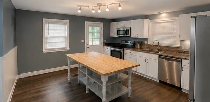 Kitchen with slate blue walls, white cabinets and a butcher block island